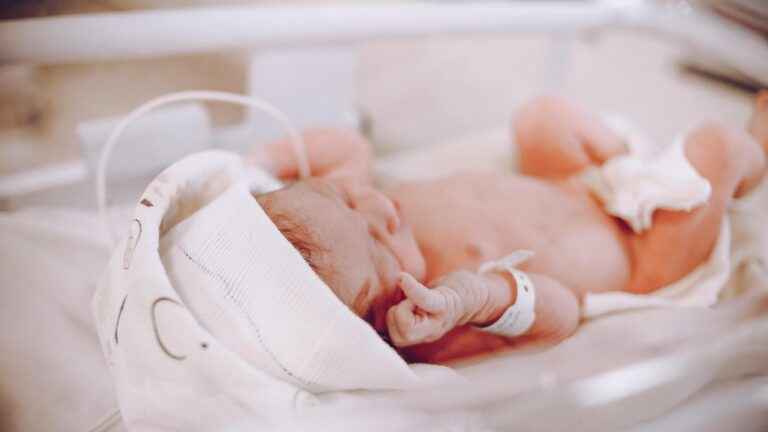 A imagem retrata um recém-nascido em uma incubadora, representando os cuidados necessários para condições clínicas como a hipoglicemia neonatal. Essa condição comum nas primeiras horas de vida exige monitoramento precoce, especialmente em prematuros ou neonatos de risco. O ambiente controlado e os cuidados médicos são essenciais para evitar complicações metabólicas e garantir um manejo adequado da glicemia neonatal.