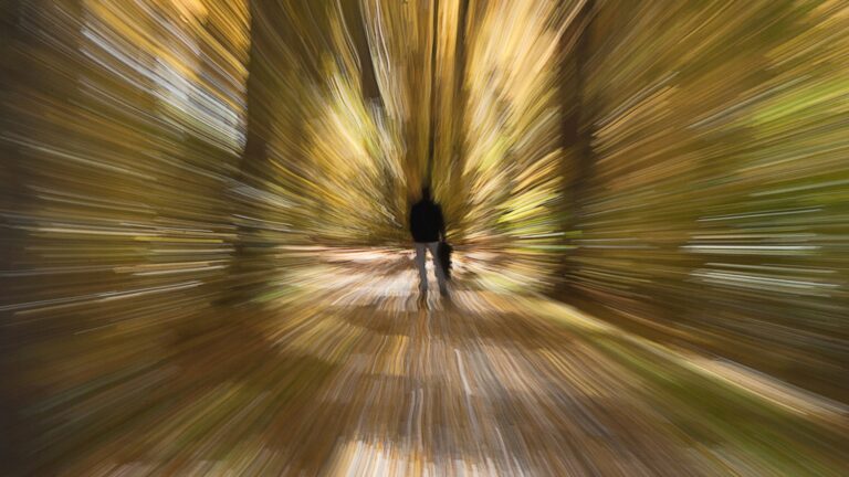 Imagem artisticamente distorcida que simula vertigem ou tontura, mostrando um homem de costas em uma trilha florestal, com o fundo em efeito de movimento radial.