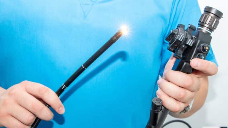 Pessoa segurando um endoscópio, com o feixe de luz aceso em sua extremidade.