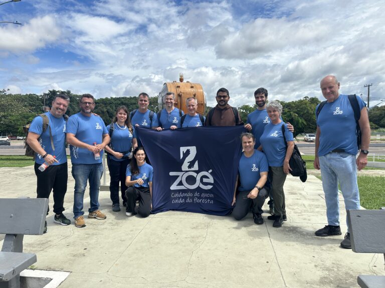 imagem com equipe de profissionais que participaram da 33ª expedição da ONG Zoé segurando uma bandeira com o logo e nome da ONG,